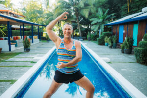 Yogi Aaron at the Blue Osa Pool deck doing a warrior 2 yoga pose with his hands in mudras