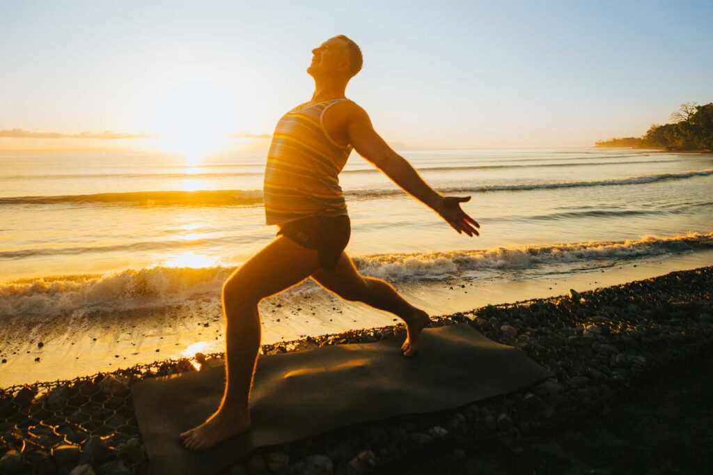 Yogi Aaron Doing Warrior 1 variation on beach at Blue Osa Yoga Retreat