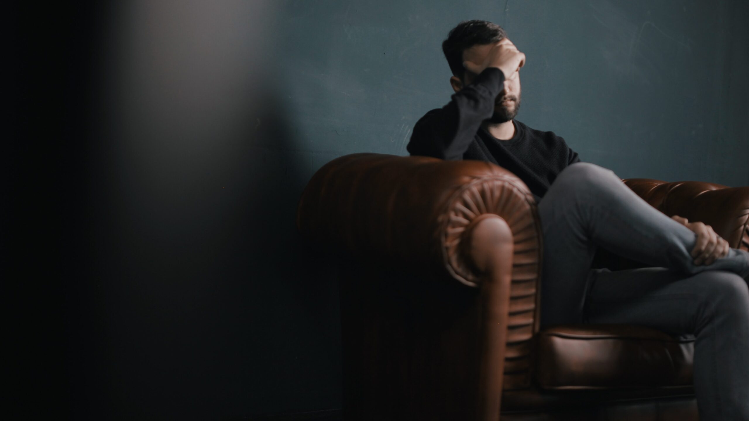 Man sitting in agony on brown leather chair