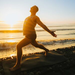 Yogi Aaron Doing Warrior 1 variation on beach at Blue Osa Yoga Retreat