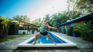 Yogi Aaron doing Warrior Pose on the Blue Osa Pool Ledge
