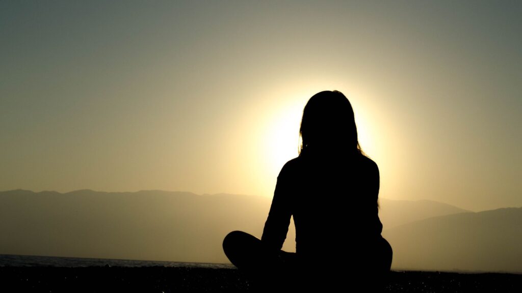 Silhouette of person meditating in nature