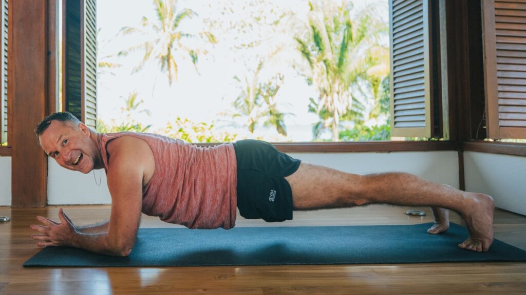 Yogi Aaron doing low plank pose on his forearms and smiling