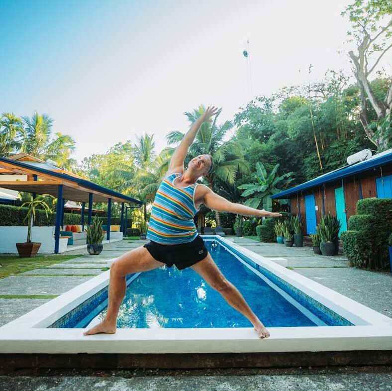Yogi Aaron doing Warrior Pose on the Blue Osa Pool Ledge