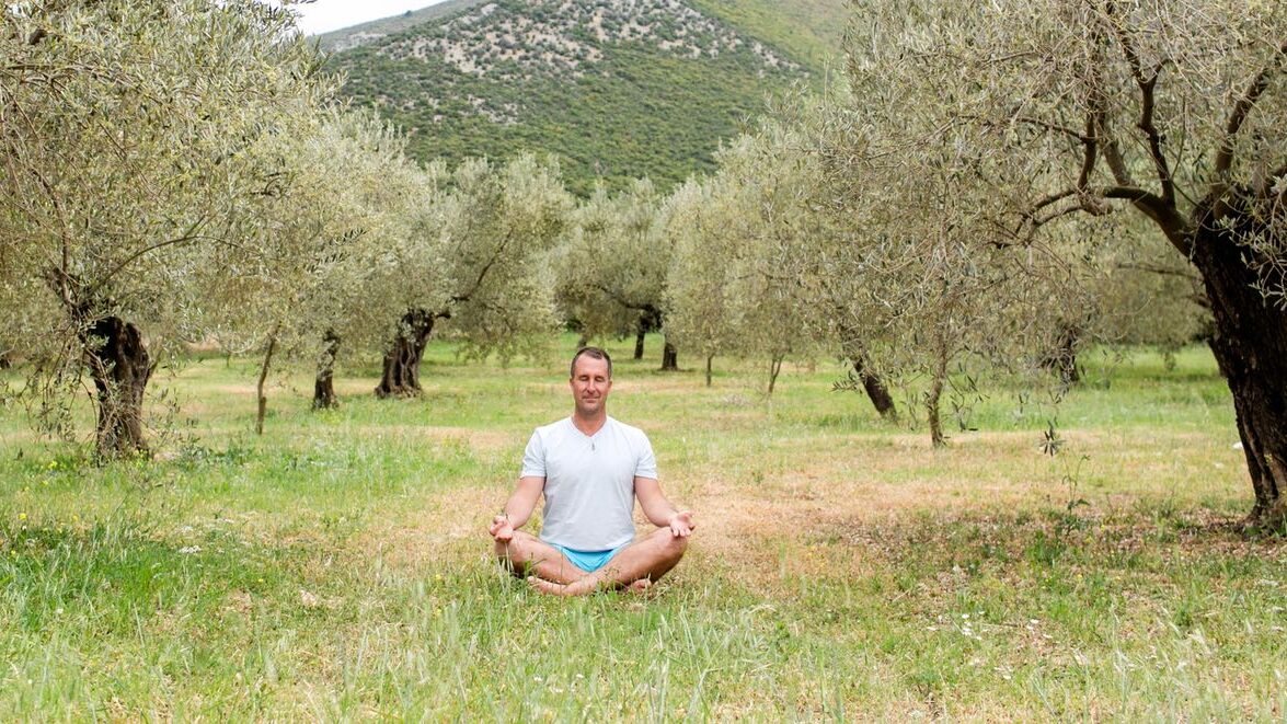 Yogi Aaron sitting on the grass meditating.