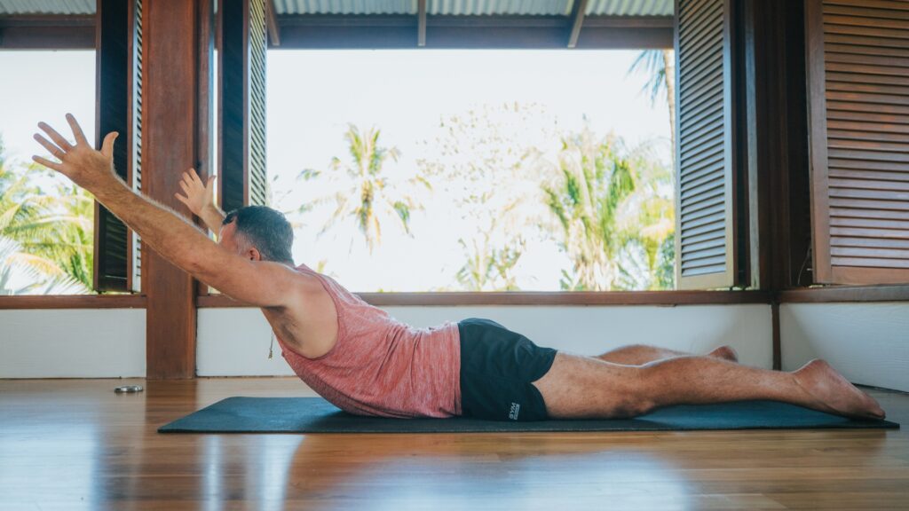 Yogi Aaron doing Shalabasana Yoga Pose with arms out in front and lifted