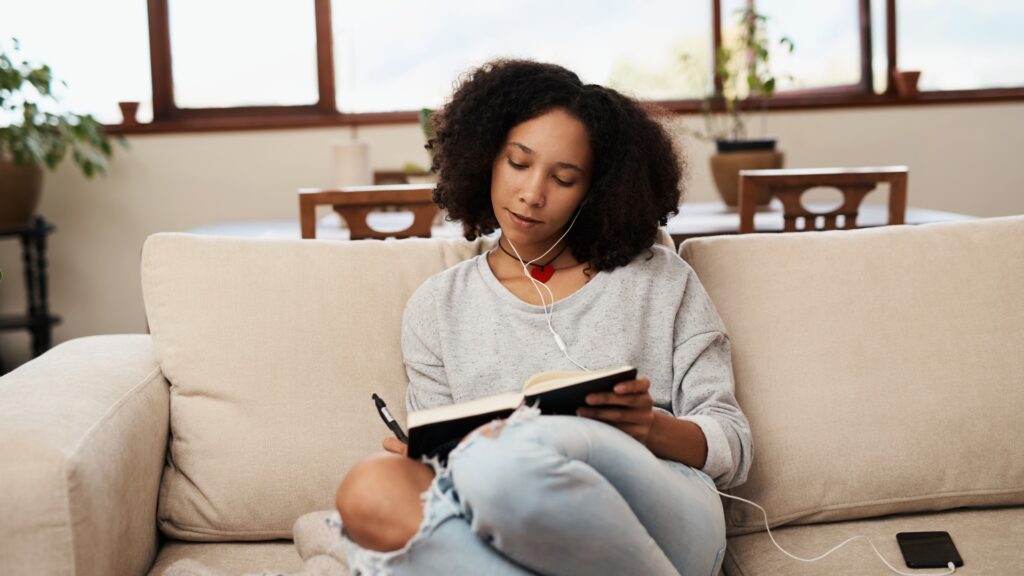 Black woman on a couch journaling