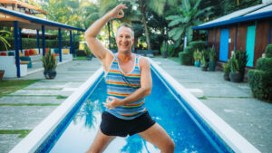 Yogi Aaron at the Blue Osa Pool deck doing a warrior 2 yoga pose with his hands in mudras
