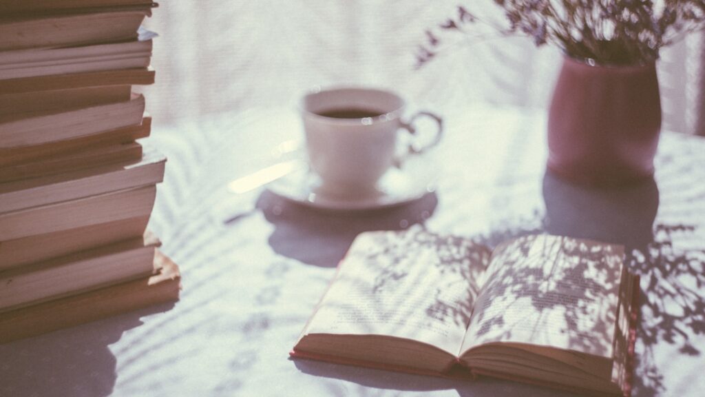 Morning ritual at table with sun shining in with coffee and inspiring book on table