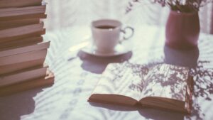 Early morning sun coming in window upon table with book and coffee
