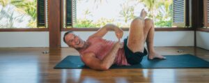 Yogi Aaron doing an AYAMA practice, smiling and pointing at core