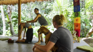 male yoga teacher adjusting student in camel pose yoga students watching