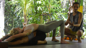 people in a partner yoga position in a yoga class