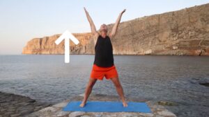 Yogi Aaron demonstrating arms overhead with deep breath in Greece