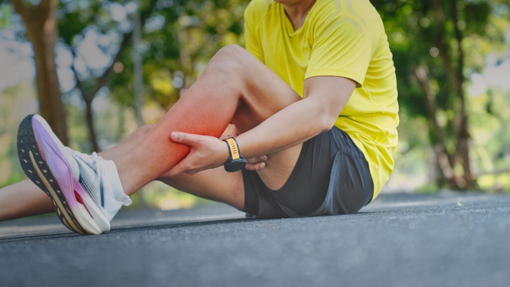 Male Runner on a track holding his Calf muscle that is cramping