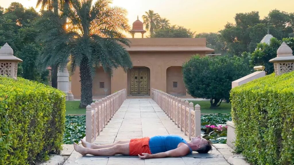 Yogi Aaron demonstrating Savasana in front of the Shiva Temple in India